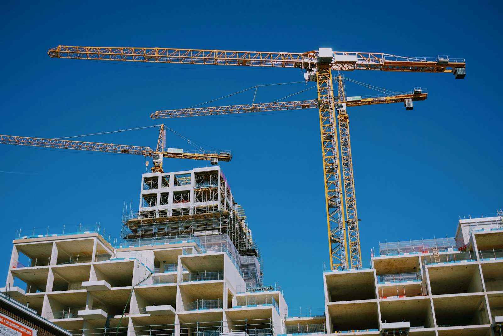 Modern multi-storey building under construction with tower cranes