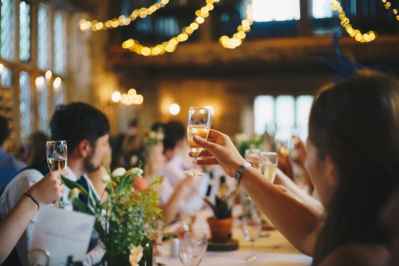 Guests raising a champagne toast under fairy lights