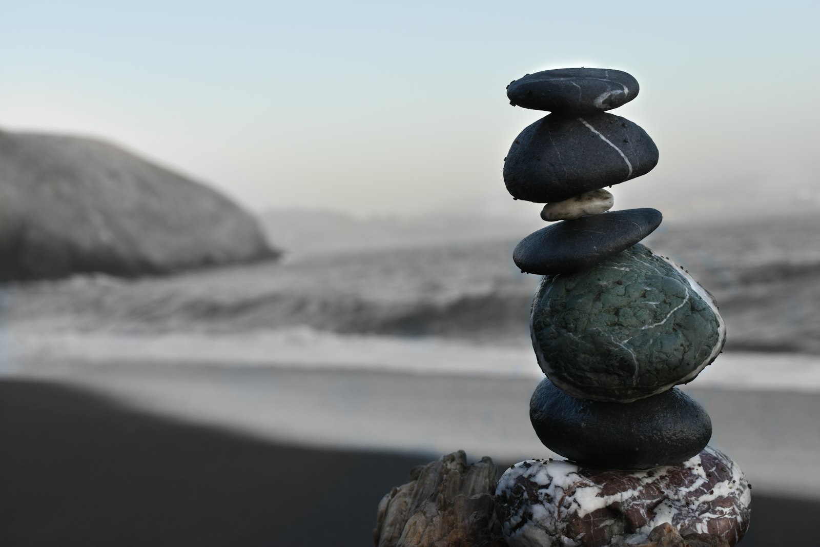 Balanced stack of smooth zen stones beside calm water