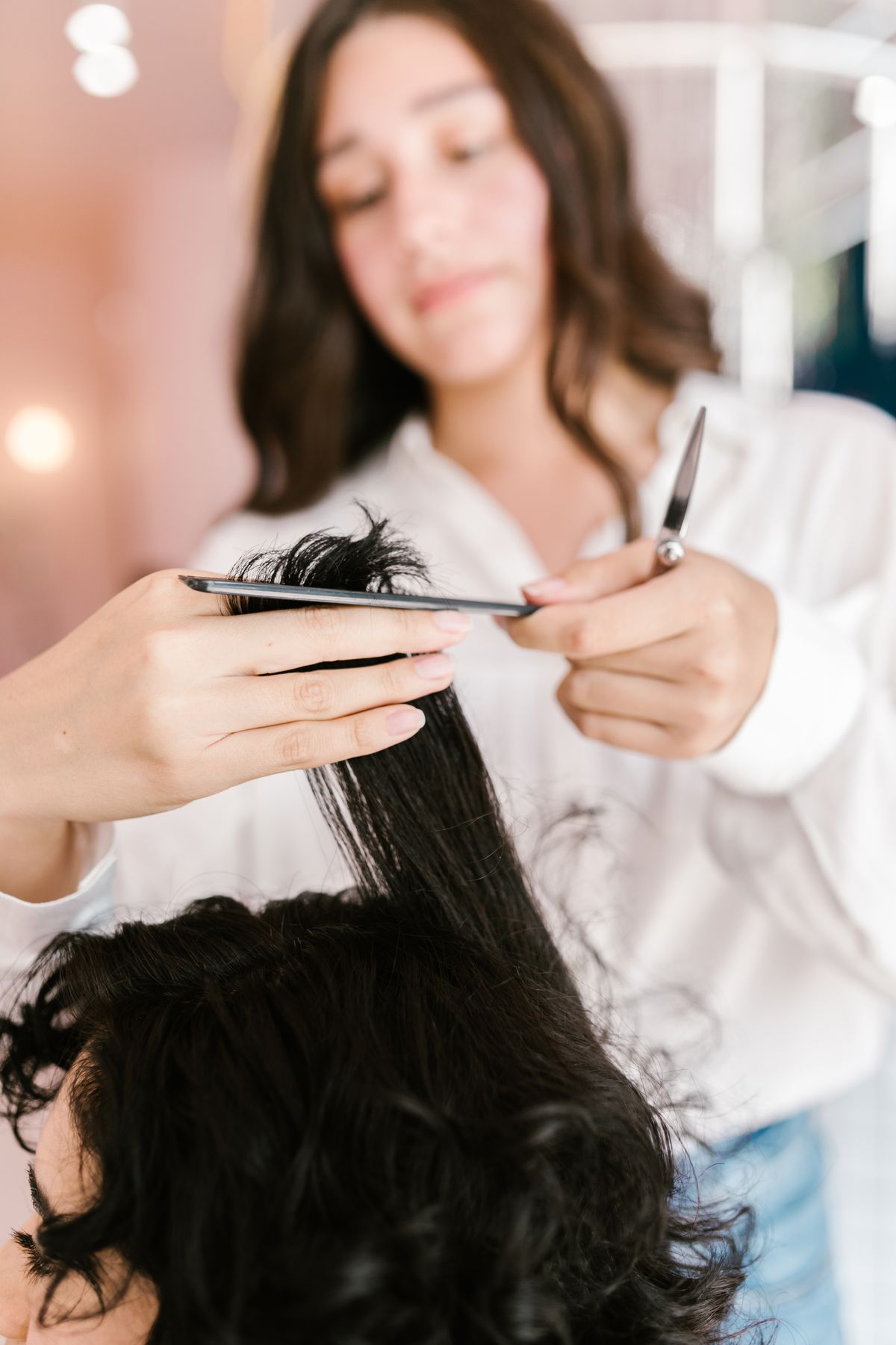 Hairstylist cutting a client's hair in a bright salon